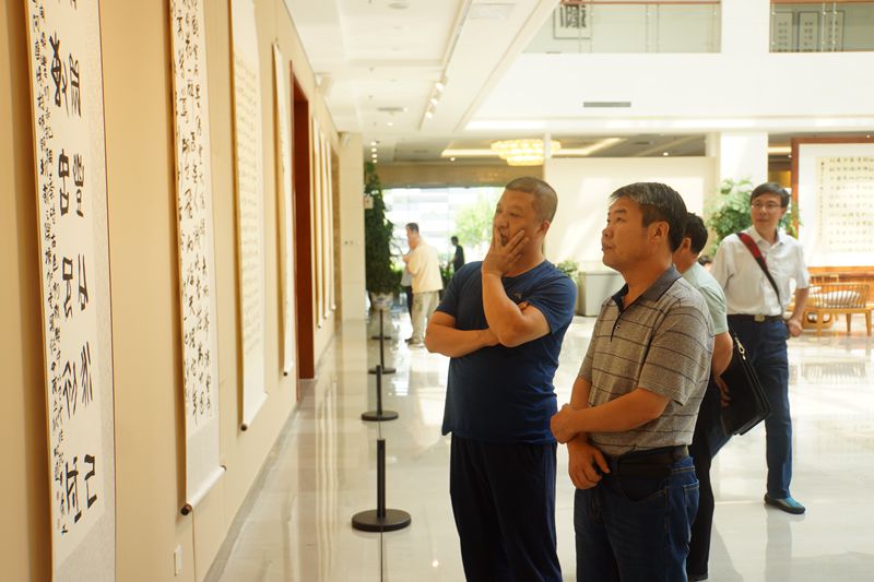插图5：参会人士品鉴展出作品