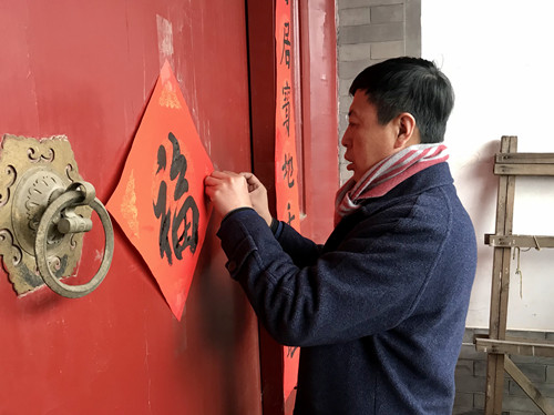 04 书法家们还和居民一同来到沙井胡同一位部队老首长的门前贴“福”字、春联_副本